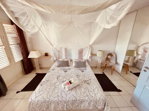 - une chambre avec un lit blanc à baldaquin dans l'établissement Sous les Tropiques…Vue mer, à Les Trois-Îlets