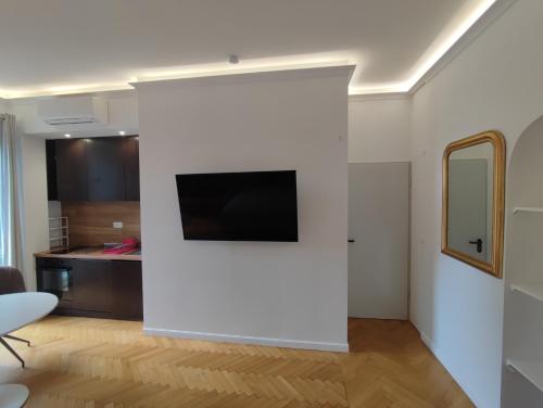 Il comprend un salon doté d'un mur blanc et d'une télévision à écran plat. dans l'établissement Nice Central Boutique Studio Apartments 1, à Nice