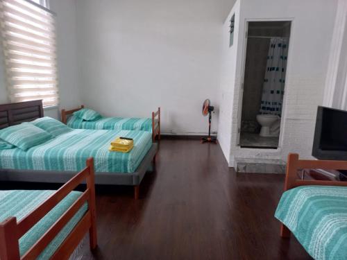 a room with two beds and a bathroom with a tub at HOSTAL BAQUEDANO IQUIQUE in Iquique