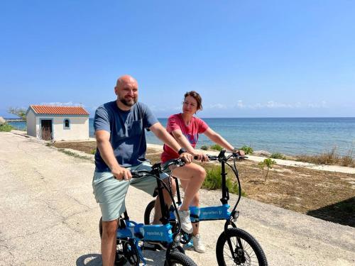 un hombre y una mujer montando una bicicleta junto al océano en Nisaki Mathraki B&B en Corfú