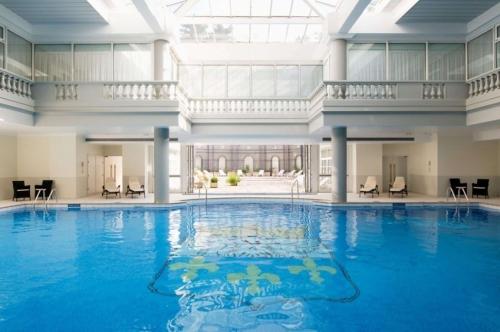 a swimming pool in a building with a large ceiling at Waldorf Astoria Versailles - Trianon Palace in Versailles