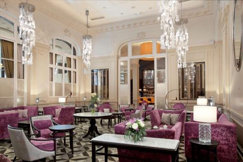 a lobby with purple chairs and tables and chandeliers at Waldorf Astoria Versailles - Trianon Palace in Versailles