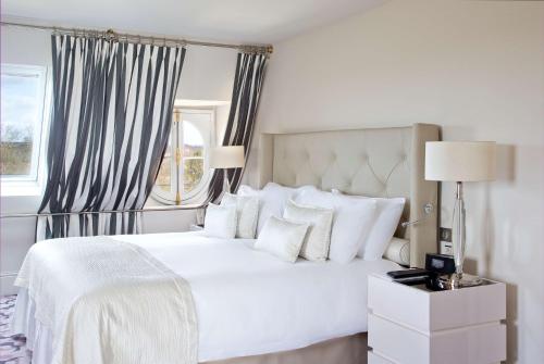 una camera bianca con un letto bianco e una finestra di Waldorf Astoria Versailles - Trianon Palace a Versailles