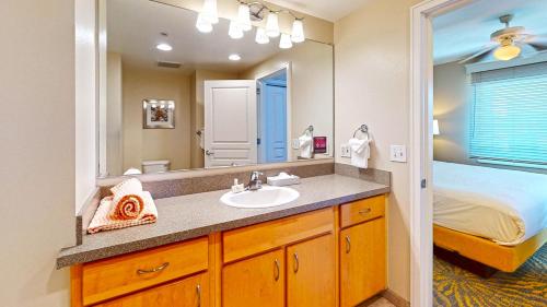 a bathroom with a sink and a bed and a mirror at WorldMark Seaside by BookTimeShares in Seaside