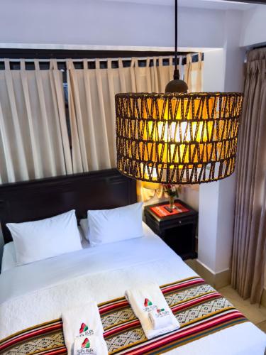 a bedroom with a bed with two pillows and a chandelier at Rupa Rupa High Jungle Eco B&B in Machu Picchu