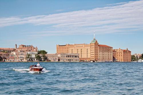 ein kleines Boot im Wasser vor einer Stadt in der Unterkunft Hilton Molino Stucky Venice in Venedig