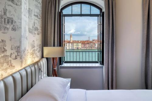 una camera da letto con finestra affacciata sulla città di Hilton Molino Stucky Venice a Venezia
