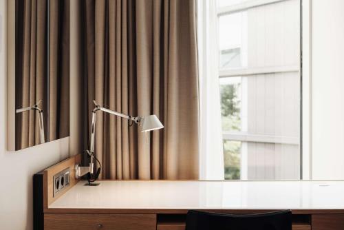 a desk with a lamp in front of a window at DoubleTree by Hilton Amsterdam Centraal Station in Amsterdam