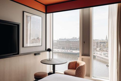 een kamer met een groot raam met uitzicht op de stad bij DoubleTree by Hilton Amsterdam Centraal Station in Amsterdam