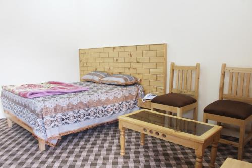 een slaapkamer met een bed en 2 stoelen bij Ghizer Inn Hotel And Resturant in Gākuch