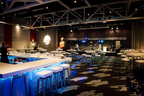 a bar with stools and tables and a man in a room at Hilton Garden Inn Leiden in Leiden