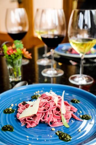 a blue plate with ham on a table with wine glasses at Twelve Hummingbirds Andes Retreat in Paute