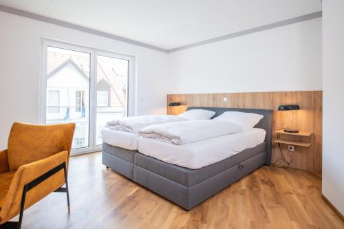 ein Schlafzimmer mit einem großen Bett und einem Stuhl in der Unterkunft Moderne Ferienwohnung direkt am Wasser in Heiligenstadt