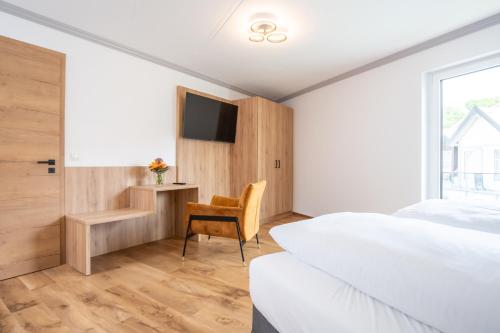 a bedroom with a bed and a tv and a chair at Moderne Ferienwohnung direkt am Wasser in Heiligenstadt