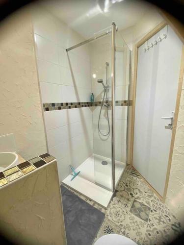 une salle de bain avec une douche avec une porte vitrée dans l'établissement La maison d Evahlia, à Creissels