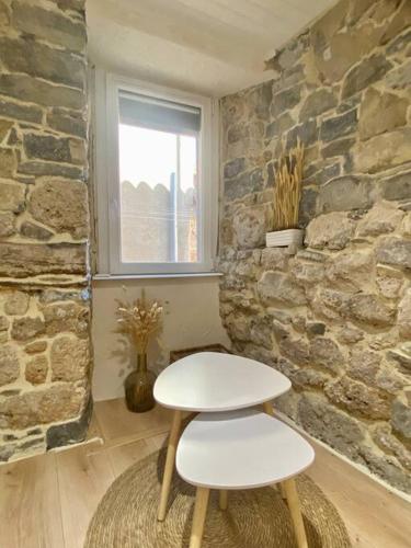 - un tabouret blanc dans une chambre avec un mur en pierre dans l'établissement La maison d Evahlia, à Creissels