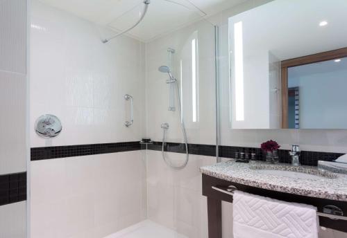 a white bathroom with a shower and a sink at Hampton by Hilton Warsaw City Centre in Warsaw