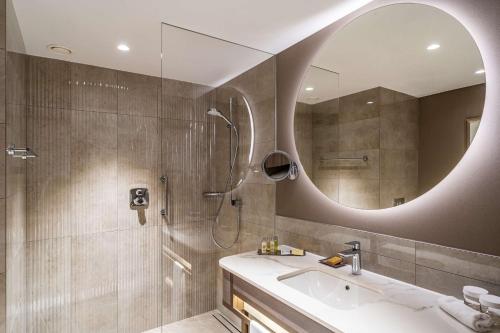 a bathroom with a shower and a sink and a mirror at Hilton Sofia in Sofia