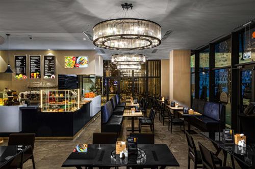 a restaurant with tables and chairs and a chandelier at DoubleTree by Hilton Minsk in Minsk