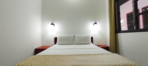 a bed in a room with two lights on the wall at HOTEL BUGANVILIA in Oiba