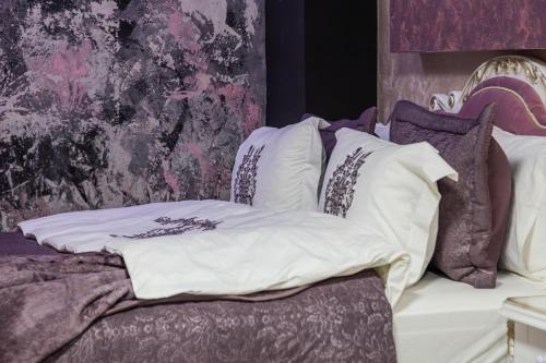 a bed with purple and white pillows on it at Aparthotel AA in Sarajevo