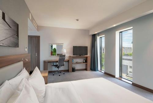 a hotel room with a bed and a desk and a tv at Hampton By Hilton Warsaw Mokotow in Warsaw