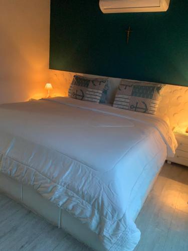 - un lit blanc dans une chambre dotée d'un mur vert dans l'établissement Sua casa, à Angra dos Reis