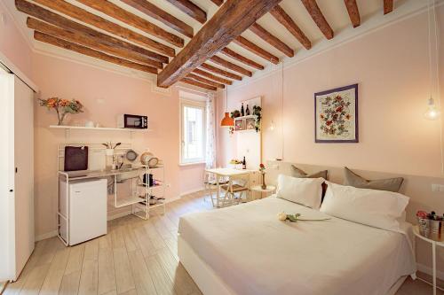 a bedroom with a white bed and a kitchen at La Casa del Vino in Parma