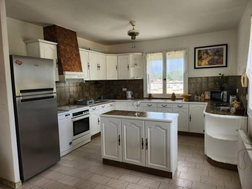 une cuisine avec des armoires blanches et un réfrigérateur en acier inoxydable dans l'établissement La Lauzière, à Cardet