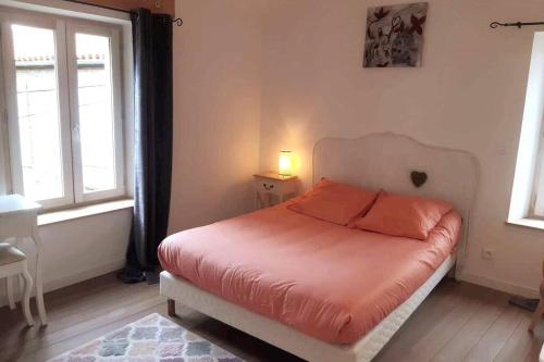 - une chambre dotée d'un lit avec des draps orange et de 2 fenêtres dans l'établissement La Manufacture d'épaulettes, à Prades