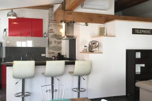 een keuken met rode kasten en witte werkbladen en krukken bij La Manufacture d'épaulettes in Prades
