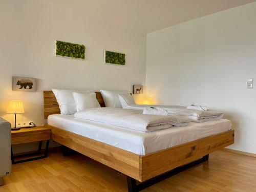 a bedroom with a large bed with white sheets at FeWo Längl -Waldluft- mit Pool und Sauna im Allgäu in Scheidegg