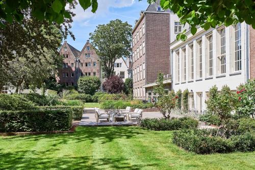 a garden with chairs and tables and buildings at Waldorf Astoria Amsterdam in Amsterdam