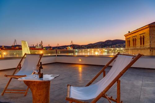 a patio with two chairs and a bottle of wine at NOS Suites in Ermoupoli