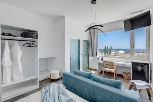 a living room with a blue couch and a view of the ocean at NOS Suites in Ermoupoli