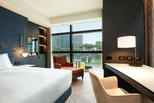 una camera d'albergo con letto, scrivania e sedia di Hilton Rome Eur La Lama a Roma