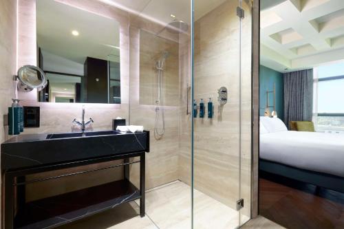 a bathroom with a shower and a sink and a bed at Hilton Rome Eur La Lama in Rome