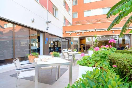 a patio with tables and chairs in a building at Hilton Garden Inn Málaga in Málaga