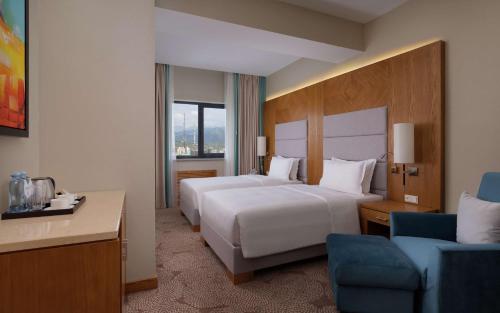 um quarto de hotel com duas camas e uma cadeira em DoubleTree by Hilton Almaty em Almaty