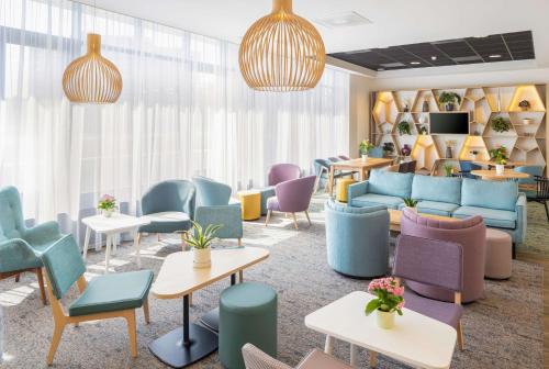 a waiting room with colorful chairs and tables at Hampton by Hilton Amsterdam Airport Schiphol in Hoofddorp
