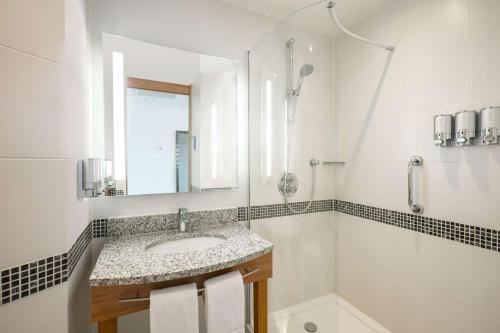 a bathroom with a sink and a shower and a mirror at Hampton by Hilton Amsterdam Airport Schiphol in Hoofddorp