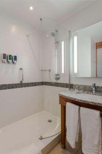 a white bathroom with a tub and a sink at Hampton by Hilton Amsterdam Airport Schiphol in Hoofddorp