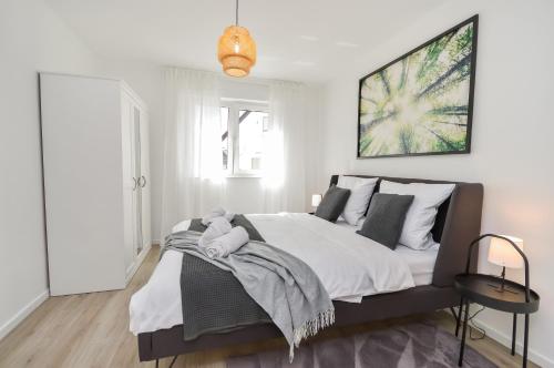 a bedroom with a large bed with white walls at Großzügig & individuell - Balkon - WiFi - TV in Bielefeld