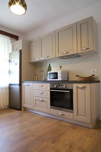 cocina con armarios blancos, microondas y nevera en Daniel City Center Apartment, en Berat
