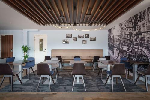 a dining room with tables and chairs and a mural at Hampton by Hilton Amsterdam Centre East in Amsterdam