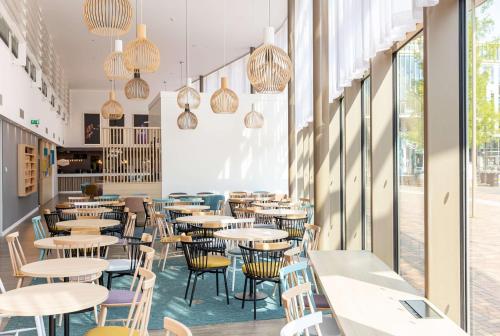 a restaurant with tables and chairs and windows at Hampton By Hilton Amsterdam Arena Boulevard in Amsterdam