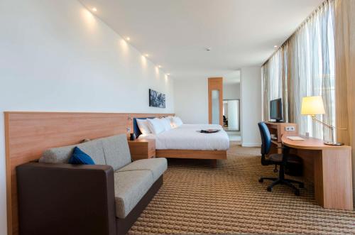 a hotel room with a bed and a couch and a desk at Hampton By Hilton Amsterdam Arena Boulevard in Amsterdam