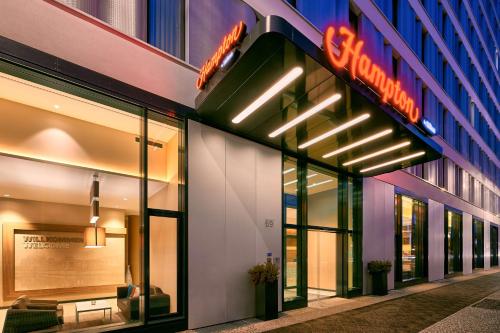 a store front of a building with a neon sign at Hampton by Hilton Berlin City Centre Alexanderplatz in Berlin