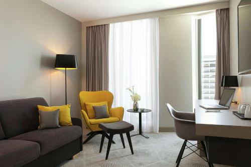 a living room with a couch and a desk in a hotel room at Hilton Garden Inn Bordeaux Centre in Bordeaux