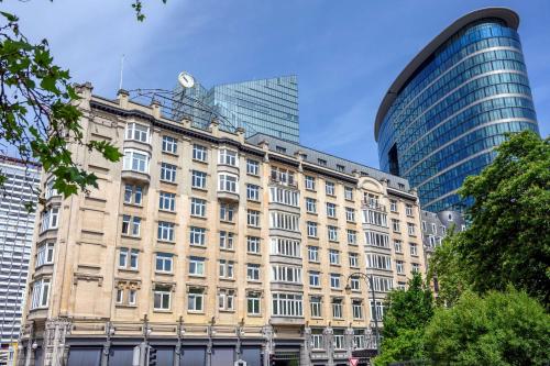 ein altes Gebäude vor einigen hohen Gebäuden in der Unterkunft DoubleTree By Hilton Brussels City in Brüssel